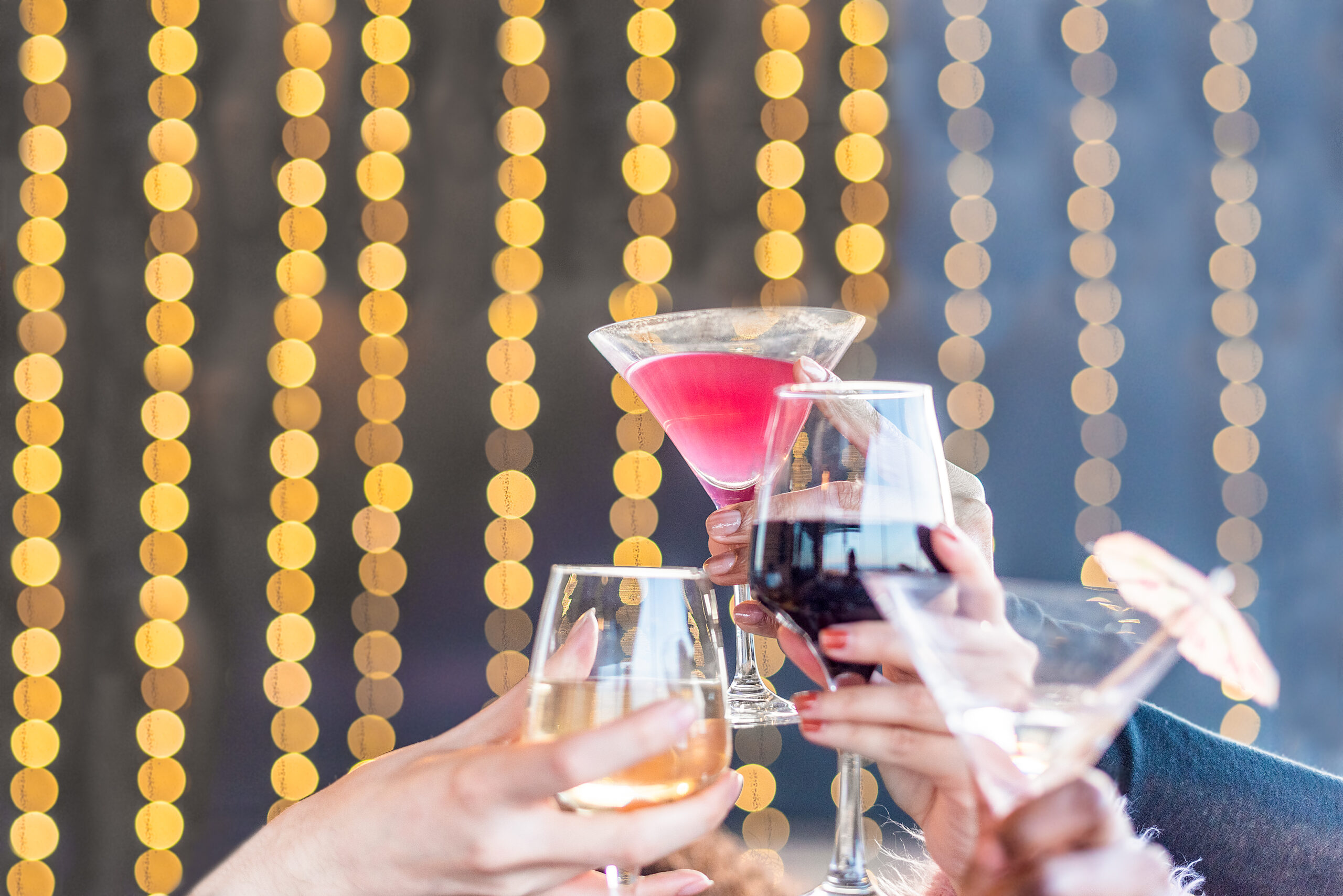 hands toasting with drinks on a blurred light background