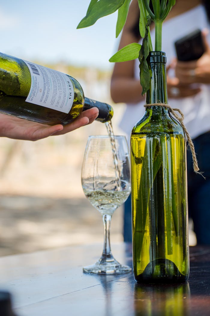Refreshing white wine being poured into a glass outdoors, capturing a summer vibe.